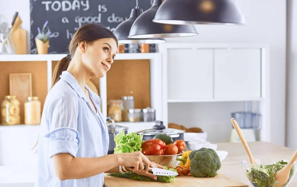 Молодая женщина готовит еду на кухне. Здоровое питание - овощи — стоковое фото