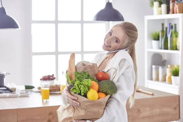 野菜提訴権と食料品の買い物袋を保持している若い女性 — ストック写真