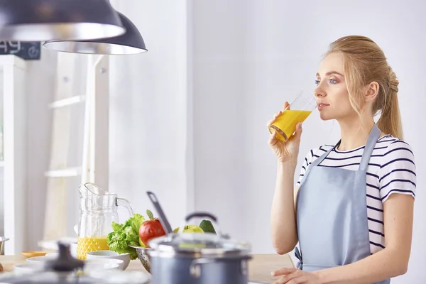 La chica en la mesa de la cocina con un vaso de zumo de naranja — Foto de Stock