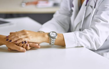 Kadın doktor hastayı sakinleştirir ve elini tutar