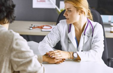 Kadın doktor hastayı sakinleştirir ve elini tutar