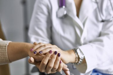 Kadın doktor hastayı sakinleştirir ve elini tutar