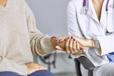 Kadın doktor hastayı sakinleştirir ve elini tutar