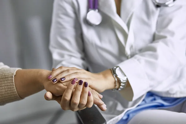 Woman doctor calms patient and holds hand — Stock Photo, Image