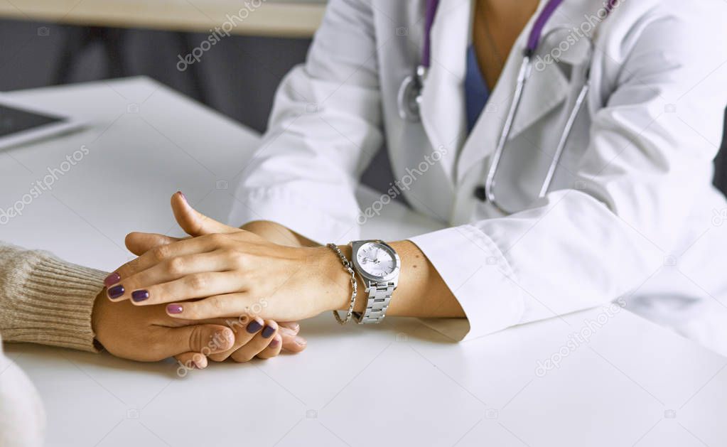 Woman doctor calms patient and holds hand