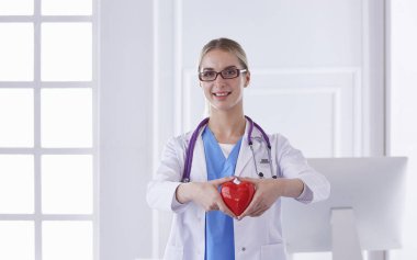 Kalbi tutan steteskoplu bir doktor, beyaz arka planda izole edilmiş.