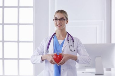 Kalbi tutan steteskoplu bir doktor, beyaz arka planda izole edilmiş.