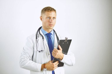 Steteskoplu beyaz önlüklü, kendine güvenen genç bir doktor.