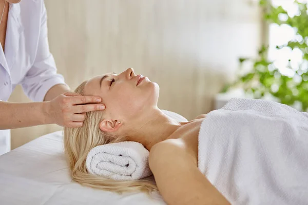 Belle femme aux yeux fermés se faisant masser dans le salon de spa — Photo