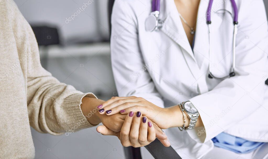 Woman doctor calms patient and holds hand