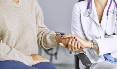 Kadın doktor hastayı sakinleştirir ve elini tutar