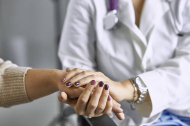 Kadın doktor hastayı sakinleştirir ve elini tutar