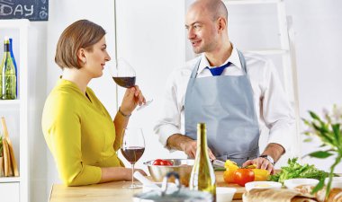 Gülümseyen genç çift mutfakta yemek pişiriyor.