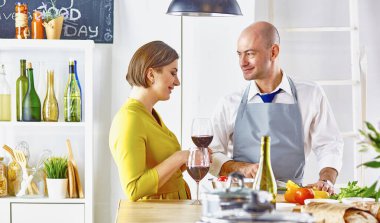 Gülümseyen genç çift mutfakta yemek pişiriyor.