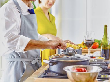 Gülümseyen genç çift mutfakta yemek pişiriyor.