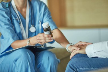 Güzel, gülümseyen kadın ilaç şişesindeki doktor hastaya sunar.