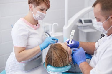 Doktor dişçi genç ve güzel bir kızın dişlerini tedavi ediyor. Dişçinin resepsiyonundaki kız. Doktor dişçi dişleri tedavi eder.