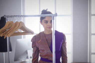 Pano raf giysi tasarımcısı ile yakınındaki beyaz arka plan üzerinde tutan güzel genç stilist