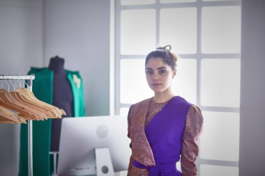 Pano raf giysi tasarımcısı ile yakınındaki beyaz arka plan üzerinde tutan güzel genç stilist