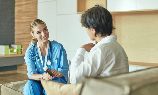 Schöne lächelnde Frau der Arzt in einer Flasche Pille bietet dem Patienten — Stockfoto