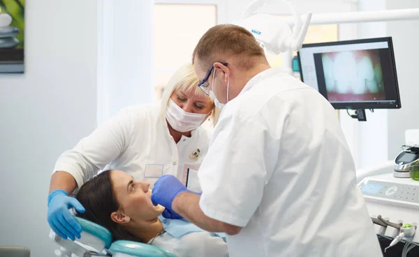 Doctor dentist treats teeth of a beautiful young girl patient. The girl on reception at the dentist. Doctor dentist treats tooth