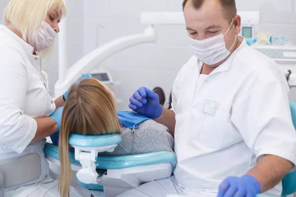 Врач-дантист лечит зубы красивой молодой пациентки. Девушка на ресепшене у дантиста. Доктор дантист лечит зуб — стоковое фото