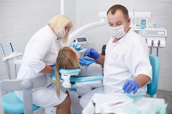 Doctor dentist treats teeth of a beautiful young girl patient. The girl on reception at the dentist. Doctor dentist treats tooth — Stock Photo, Image