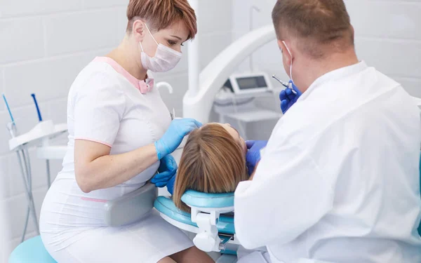 Lekarz dentysta leczy zęby pięknej młodej pacjentki. Dziewczyna z recepcji u dentysty. Lekarz dentysta leczy zęby. — Zdjęcie stockowe