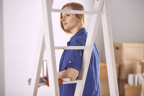 Bella giovane donna su una scala di legno bianca. Pronto a riparare la stanza. Donne concetto di lavori domestici — Foto Stock