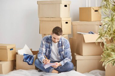 Taşındıktan sonra yeni dairede kutuları olan yakışıklı bir adam.