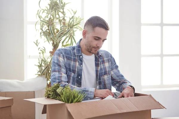 Красивый мужчина с коробками в новой квартире после переезда — стоковое фото