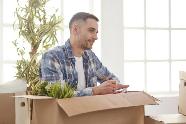 Hombre guapo con cajas en el nuevo apartamento después de mudarse —  Fotos de Stock