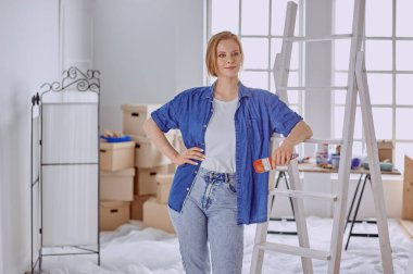 Beyaz tahta bir merdiven üzerinde güzel bir genç kadın. Odayı onarmaya hazırız. Kadın ev işi konsepti