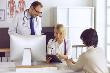 Orta yaşlı erkek doktor bir meslektaşının çalışmasına eşlik ediyor.