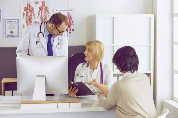 Orta yaşlı erkek doktor bir meslektaşının çalışmasına eşlik ediyor. — Stok fotoğraf