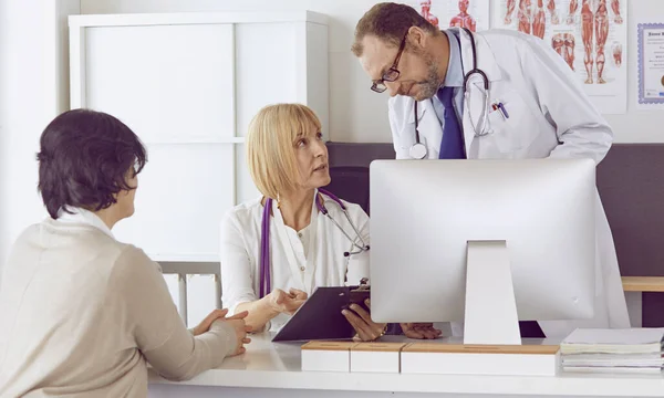 Orta yaşlı erkek doktor bir meslektaşının çalışmasına eşlik ediyor. — Stok fotoğraf