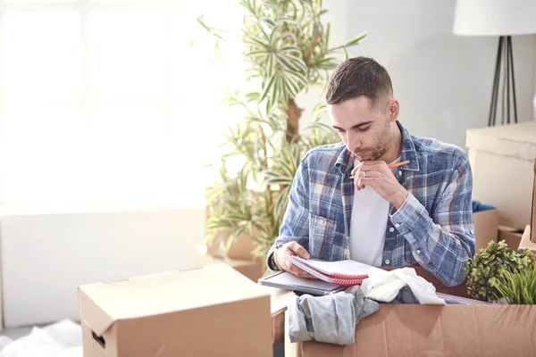 Hombre guapo con cajas en el nuevo apartamento después de mudarse —  Fotos de Stock