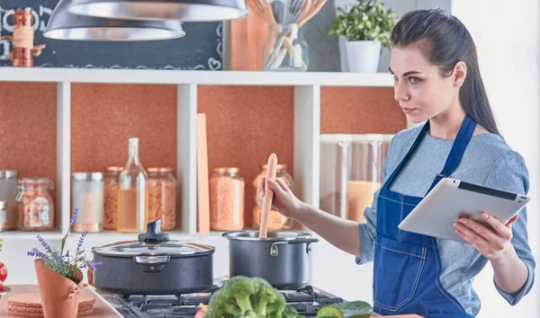 Happy woman looking recipe tablet kitchen reading cooking