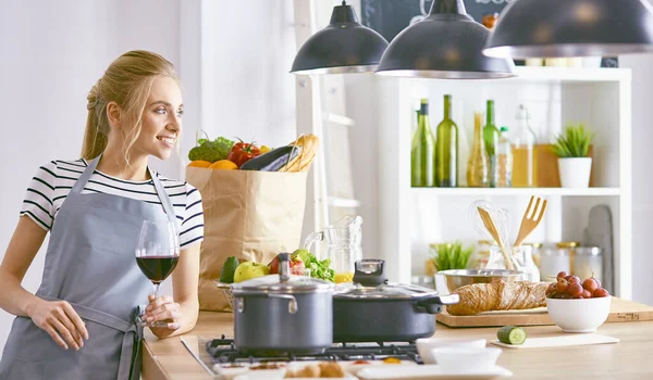 Beautiful woman in kitchen is drinking red wine — Stock Photo, Image