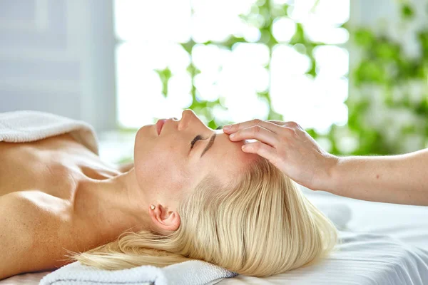 Belle femme aux yeux fermés se faisant masser dans le salon de spa — Photo