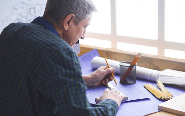 Плотник-инженер, работающий над проектом ноутбука и эскиза
