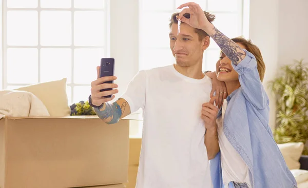 Feliz joven pareja sonriente mostrando un par de llaves de su nueva casa — Foto de Stock