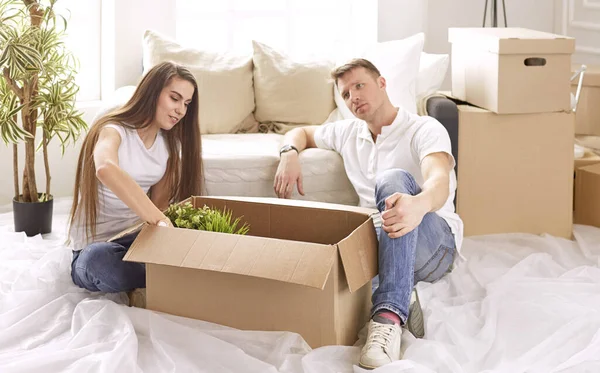 幸せなカップルの肖像ノートパソコンを一緒に新しい家の中に座って、箱に囲まれて見て — ストック写真