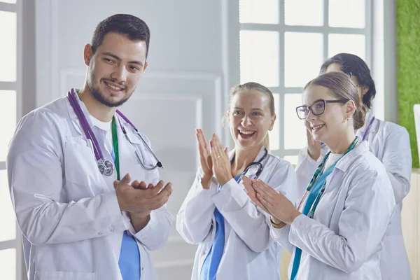 Happy medical team comprising male and female doctors smiling broadly and giving a thumbs up of success and hope