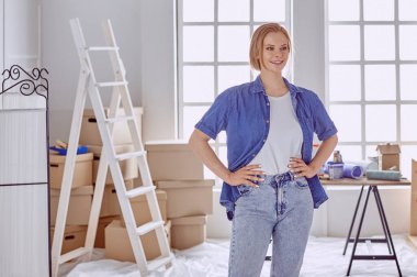 Beyaz tahta bir merdiven üzerinde güzel bir genç kadın. Odayı onarmaya hazırız. Kadın ev işi konsepti