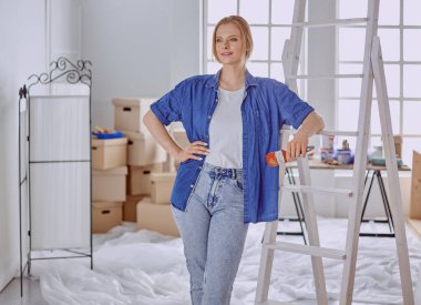 Beyaz tahta bir merdiven üzerinde güzel bir genç kadın. Odayı onarmaya hazırız. Kadın ev işi konsepti