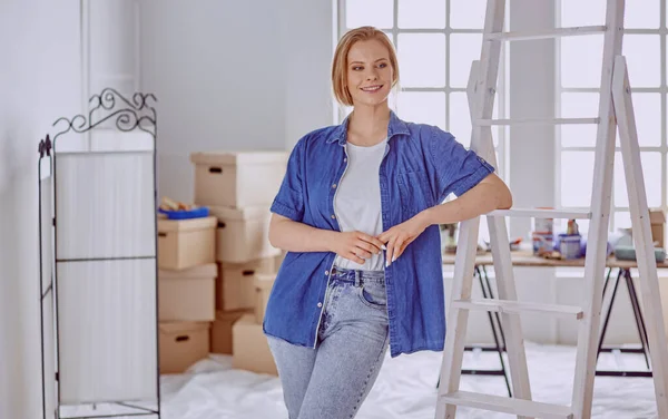 Beautiful young woman on a white wooden stepladder. Ready to repair the room. Women housework concept