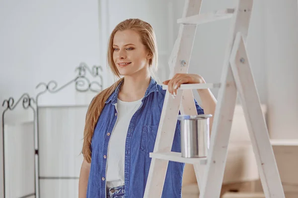 Красивая молодая женщина на белой деревянной лестнице. Готовы отремонтировать комнату. Концепция работы по дому — стоковое фото