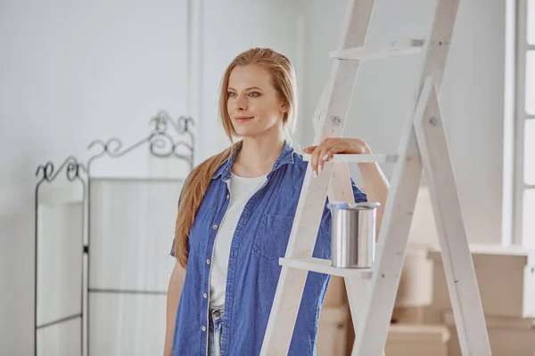 Hermosa joven en una escalera de madera blanca. Listo para reparar la habitación. Concepto de tareas domésticas — Foto de Stock