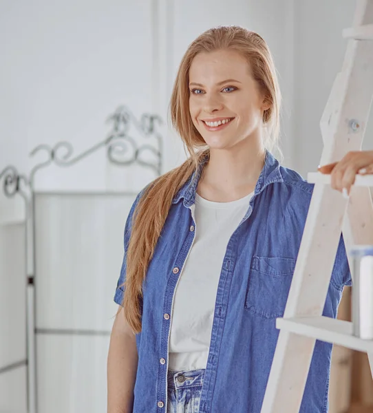 Hermosa joven en una escalera de madera blanca. Listo para reparar la habitación. Concepto de tareas domésticas — Foto de Stock